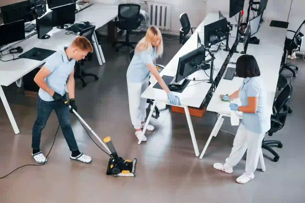 Équipe en polos bleus entretenant les sols et les postes de travail d’un bureau